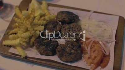 Woman eating meat patties with potatoes and vegetables