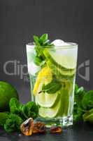 Refreshing mint cocktail mojito with rum and lime, cold drink or beverage with ice on black background