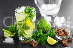 Refreshing mint cocktail mojito with rum and lime, cold drink or beverage with ice on black background