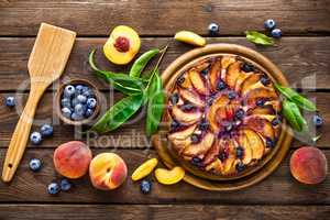 Peach cheese cake or pie with fresh blueberry on wooden rustic background, top view, closeup