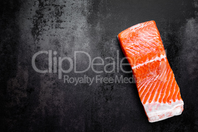 Raw salmon or trout sea fish fillet on black metal background, top view