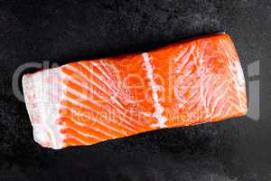 Raw salmon or trout sea fish fillet on black metal background, top view