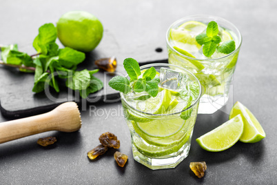 Summer mint lime refreshing cocktail mojito with rum and ice in glass on black background top view