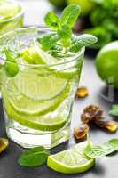 Summer mint lime refreshing cocktail mojito with rum and ice in glass on black background