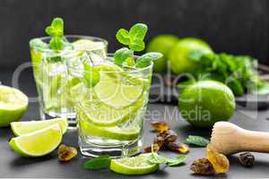 Summer mint lime refreshing cocktail mojito with rum and ice in glass on black background