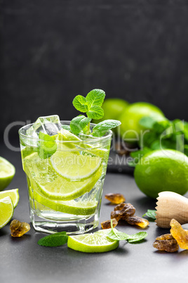 Summer mint lime refreshing cocktail mojito with rum and ice in glass on black background