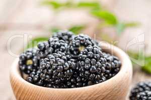 Fresh blackberry with leaves on wooden background close up