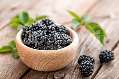 Fresh blackberry with leaves on wooden background close up