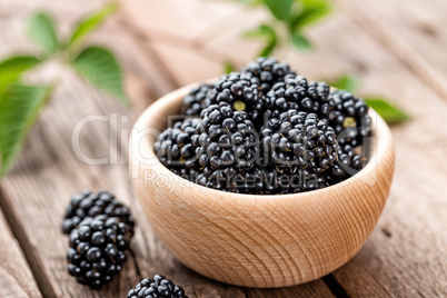 Fresh blackberry with leaves on wooden background close up