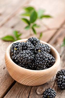 Fresh blackberry with leaves on wooden background close up