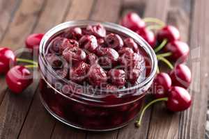 Berries cherry with syrup in a glass jar. Canned fruit