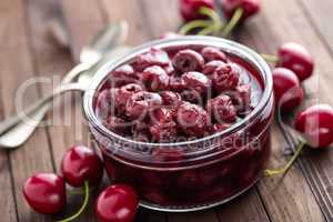 Berries cherry with syrup in a glass jar. Canned fruit