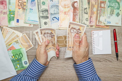 Banker counting Convertible mark at his office table, Empty Notebook World currencies around him