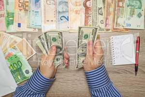 Banker counting Dollars at his office table, Empty Notebook World currencies around him