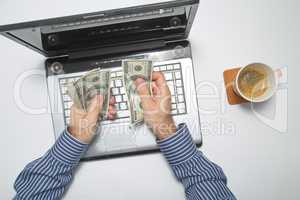 Businessman working on laptop and counting money while as he drinks coffee