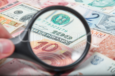 Magnifying Glass on the American Dollars between world currencies.