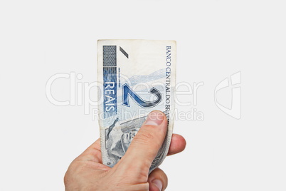 Male hand holding National currency of Brasil.