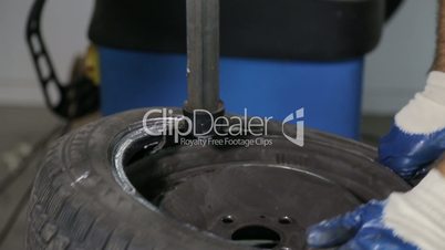 Man put on tire on car wheel by special tool,