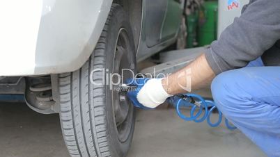 Automobile mechanic unscrews wheel to change tire