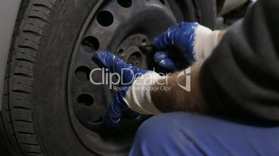 Automobile mechanic unscrews wheel to change tire
