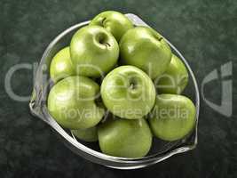 Glass bowl filled with green apples on green background