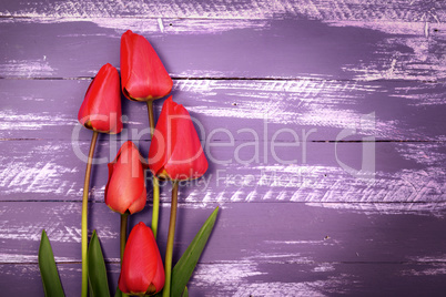 Bouquet of five red tulips on a wooden surface