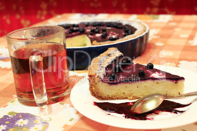 piece of pie with bilberry on the plate and cup of tea