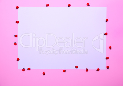 White sheet of paper on a pink surface,