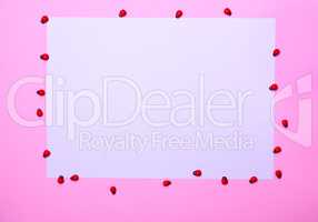 White sheet of paper on a pink surface,