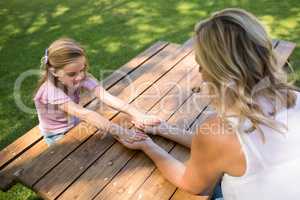 Mother and daughter holding hands on picnic table