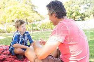 Father talking to son at picnic in park