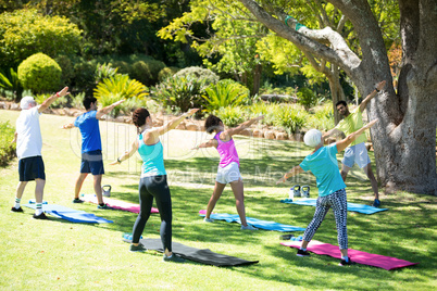 Group of people performing stretching exercise in the park