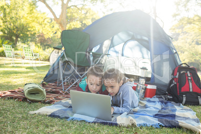 Siblings using laptop outside the tent