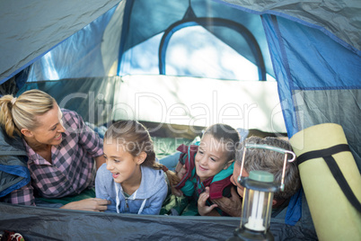 Smiling family talking while lying in the tent