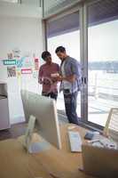 Businesswoman and businessman discussing over digital tablet in office