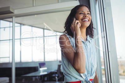 Smiling businesswoman talking on phone by window