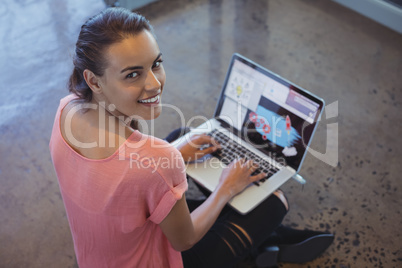 Portrait of graphic designer working on laptop while sitting at floor