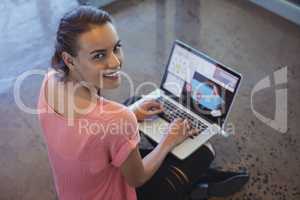 Portrait of graphic designer working on laptop while sitting at floor