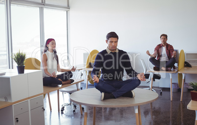 Business colleagues practicing yoga at office