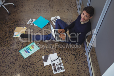 Portrait of businessman sitting on floor while working in creative office