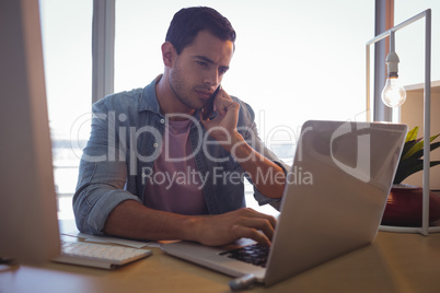 Serious businessman talking on phone while working at office