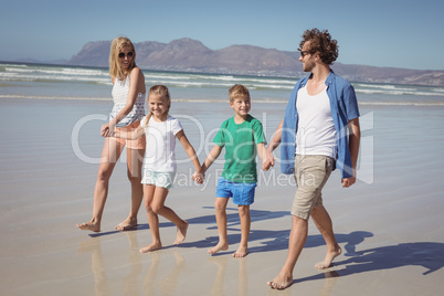 Happy family holding hands while walking at beach