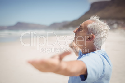 Side view of senior man with arms outstretched at beach