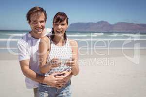 Portrait of cheerful couple holding mobile phone at beach