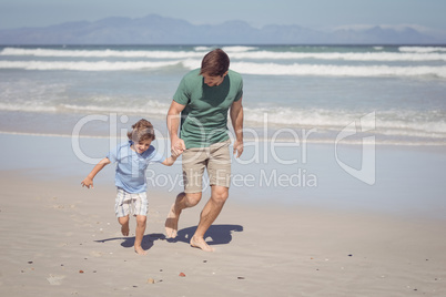 Happy boy with father running at beach