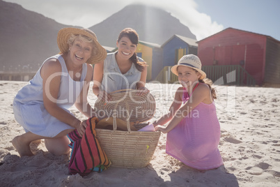 Portrait of multi-generation family by picnic basket at beach