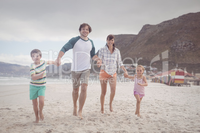 Portrait of family holding hands on sand at beach