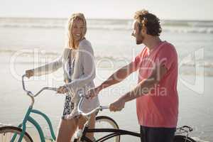 Happy young couple with bicycles at beach