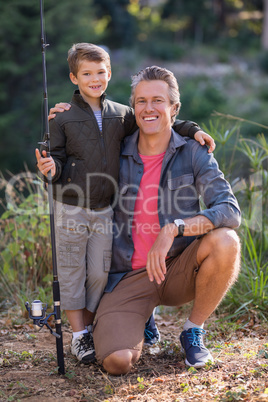 Father and son posing with fishing rod on field