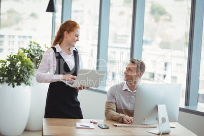 Smiling executives interacting while working at desk